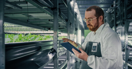 Portrait of a Biologist Analyzing Fresh Crops at Modern Vertical Farm Facility. Agricultural...