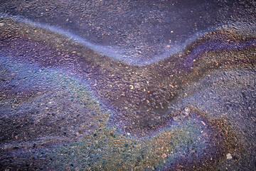 Bright spot splash of oil or gasoline on asphalt after rain
