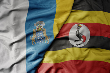 big waving national colorful flag of uganda and national flag of canary islands .