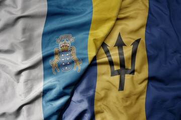 big waving national colorful flag of barbados and national flag of canary islands .