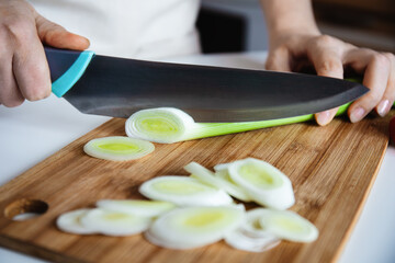 Chef Slicing Leek on Bamboo Cutting Board