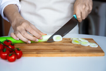 Chef Slicing Leeks on Wooden Board