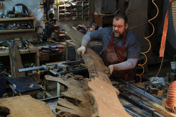 An artisan feeds a rugged slab of wood through a table saw, transforming it with each precise cut. The workshop buzzes with activity.