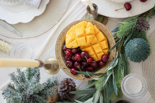 Mango and cherries in bowl on decorated Christmas table