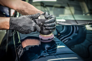 Car detailing and polishing concept. Hands of professional car service male worker, with orbital...