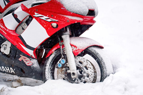 Minsk, Belarus. Jan 24, 2024. Yamaha YZF R6 parked on snowy parking lot in residential area during blizzard. Snow covered red motorcycle on the street. Parked motorbike in snow. Wheel stuck in snow