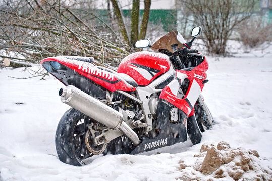 Minsk, Belarus. Jan 24, 2024. Yamaha YZF R6 parked on snowy parking lot in residential area during blizzard. Snow covered red motorcycle on the street. Parked motorbike in snow. Rear view