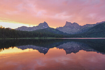 Amazing pink sunset on mountain lake Svetloye. Clear water with mirror reflection. Power of nature....