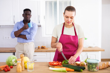 Pensive woman in apron cutting vegetables for vegetables at home