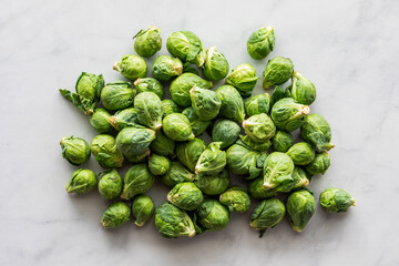 Top down view of a pile of fresh brussel sprouts, on a marble surface.