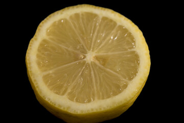 Half yellow lemon with dark black background horizontally Citrus aurantifolia