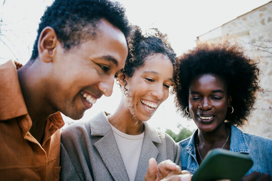 Happy woman sharing smart phone with friends at backyard