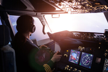 A female pilot controls a large passenger plane. View from the back - obrazy, fototapety, plakaty