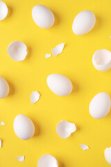 Minimalistic Easter background. White Easter eggs and shells on a bright yellow background. Top view.