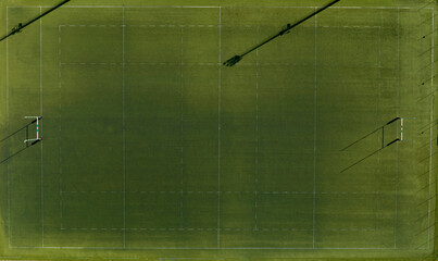 Perpendicular aerial view of an artificial turf rugby field. The sports facility is empty.

