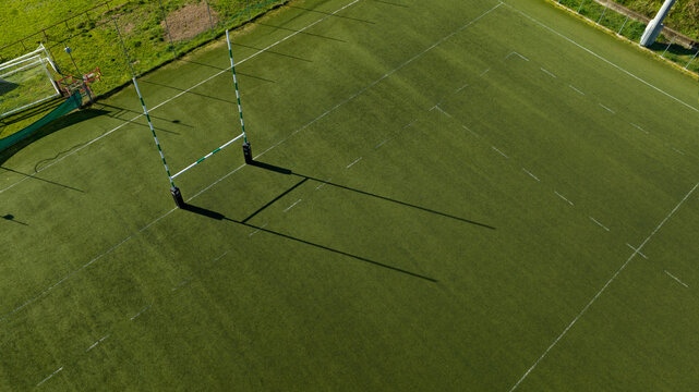 Aerial view of rugby goal post in a stadium on a sunny day. It is an artificial turf rugby field. The sports facility is empty.