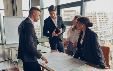 Group of professional team design engineers working with project documents in modern office