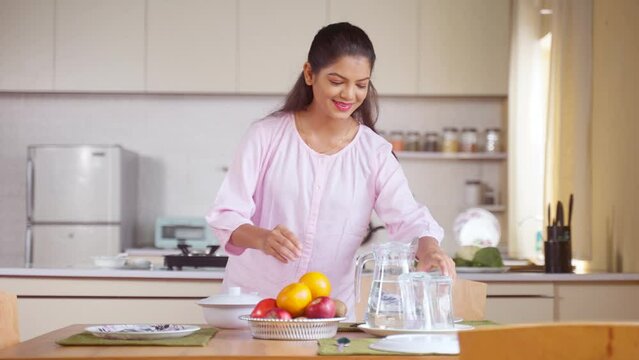 Happy Indian woman preparing dining table for breakfast at morning - concept daily routine, family responsibility and housework
