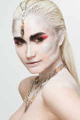 Close-up portrait of a beautiful girl painted with body painting in chains, bracelets and other jewelry