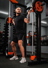 A large bearded man in the gym performs a squat exercise with a barbell. Preparation of a...