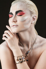 Close-up portrait of a beautiful girl painted with body painting in chains, bracelets and other jewelry