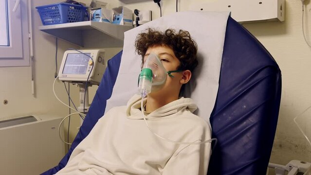 Teenager in hospital making an inhalation using an oxygen mask. Treatment of respiratory disease