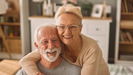 Happy elderly couple hugging indoors