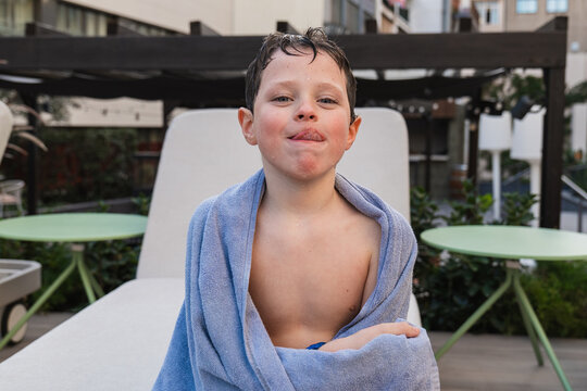 Young boy wrapped in towel after swimming, smirking