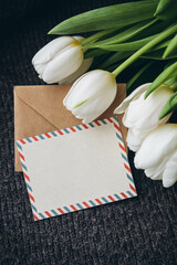Spring composition with a postcard and a bouquet of white tulips, close-up. Blank postal greeting card and bouquet of white fresh tulip flowers, copy space.