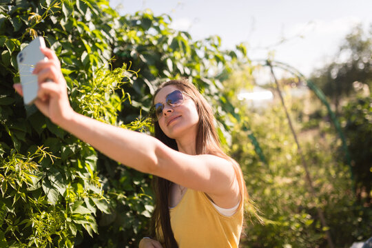 Woman taking selfie in sunny green garden