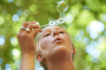 Lady, game and bubbles of water and soap, freedom with happiness, summer and blurred background. Outdoors, gen z and play in park for peace and activity with wand in sunshine, calm and nature