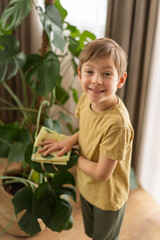 A little boy helps with cleaning around the house and taking care of the plants. Spring cleaning concept
