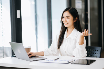  Asian businesswoman working with working notepad, tablet and laptop documents talking on the tablet and laptop