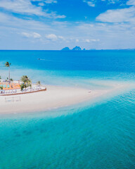 Drone aerial view at Koh Muk a tropical island with palm trees and soft white sand, and a turqouse colored ocean in Koh Mook Trang Thailand