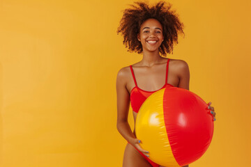 Funny young happy African American woman in red swimsuit having fun holding inflatable ball and...