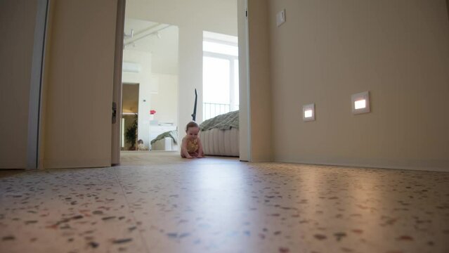 A cheerful infant explores the home on all fours, radiating joy with a wide smile as it crawls across a speckled floor.