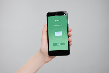 Got new message. Woman holding smartphone on grey background, closeup
