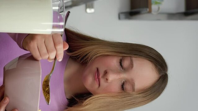 Morning routine girl eating cereal with milk in modern kitchen vertical video close-up healthy tasty food. Cereal with milk energy for school cozy start day happy child moments cereal with milk.