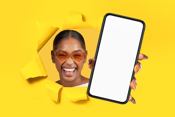 black woman shows cellphone in hand breaking through yellow paper