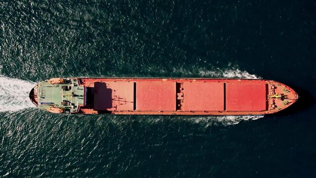 Aerial top view of large cargo ship traveling over blue ocean sea for logistics import export, shipping or transportation
