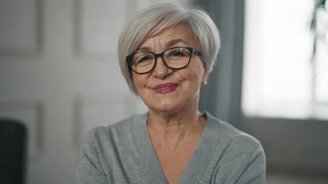 Portrait face cheerful senior woman looks at camera smiling. Retired good looking positive pensioner female with make-up, caucasian elderly lady. Old age lifestyle, wellbeing seniors concept.