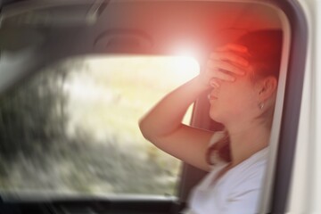 Fototapeta na wymiar Blured photo of a woman sitting in the car suffering from vertigo or dizziness or other health problem of brain or inner ear.