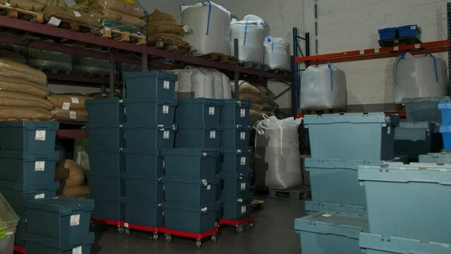 Warehouse filled with plastic containers and packaged goods. Storehouse maintains sense of order and cleanliness with clear pathways