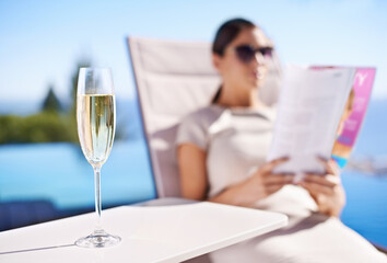 Relax, pool and woman with champagne, magazine and reading in lounge chair on business trip....