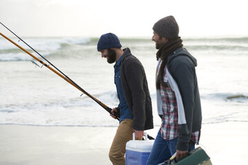 Nature, fishing and men walking on beach together with cooler, tackle box and holiday conversation. Ocean, fisherman and friends with rods, bait and tools at waves on winter morning vacation at sea.