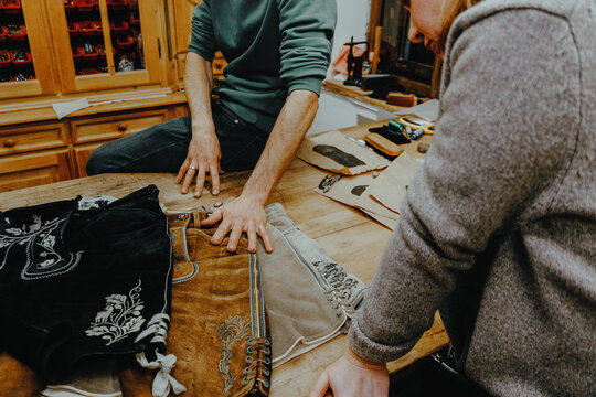 A master tailor shows an embroidered pattern on leather.