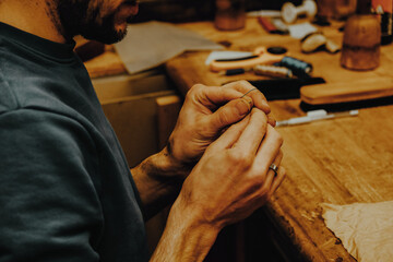 A master tailor shows an embroidered pattern on leather.