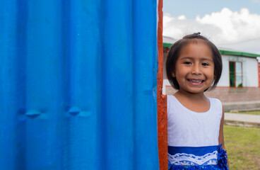 niña india sonriendo y mirando al frente mientras juega en el patio de su casa 