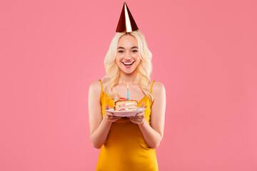 Joyous young woman with cake looking delighted at party