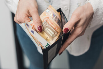 Woman's hands taking out money from wallet, euro banknote cash